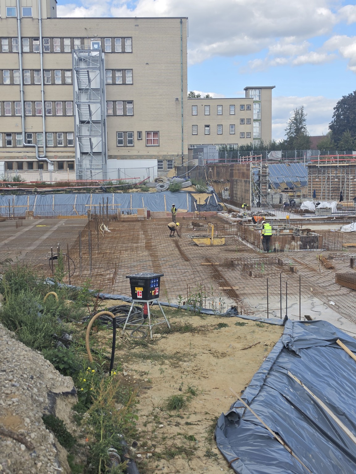 Reinforcement mats and starter bars beside the hospital building.